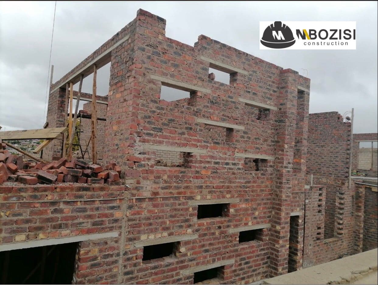 Branded Mbozisi photo of a brick shell building under construction with concrete lintels in place.