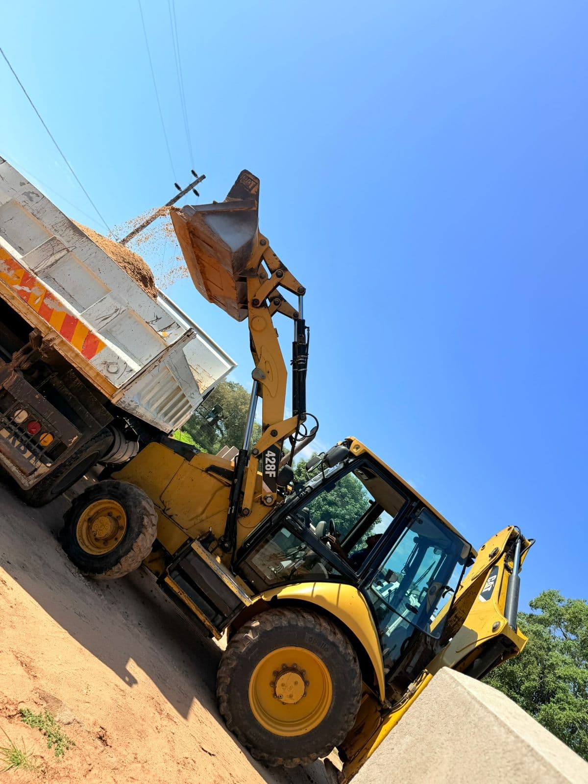 Loader excavator transferring material into a tip truck on site.