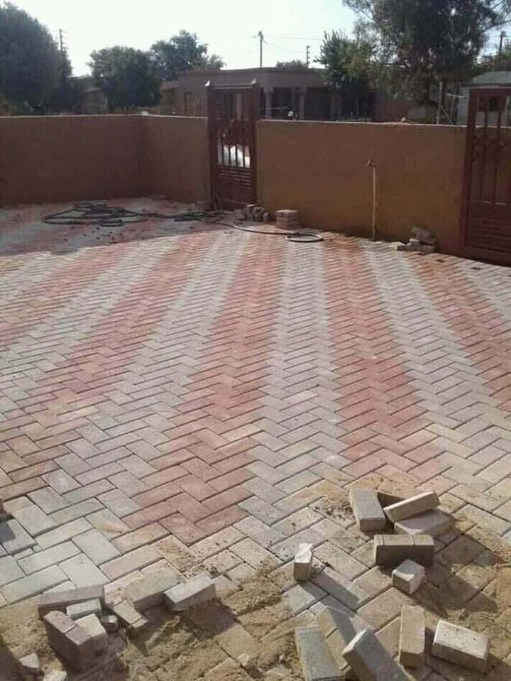 Completed herringbone paving laid across a residential courtyard with a boundary wall and gates.