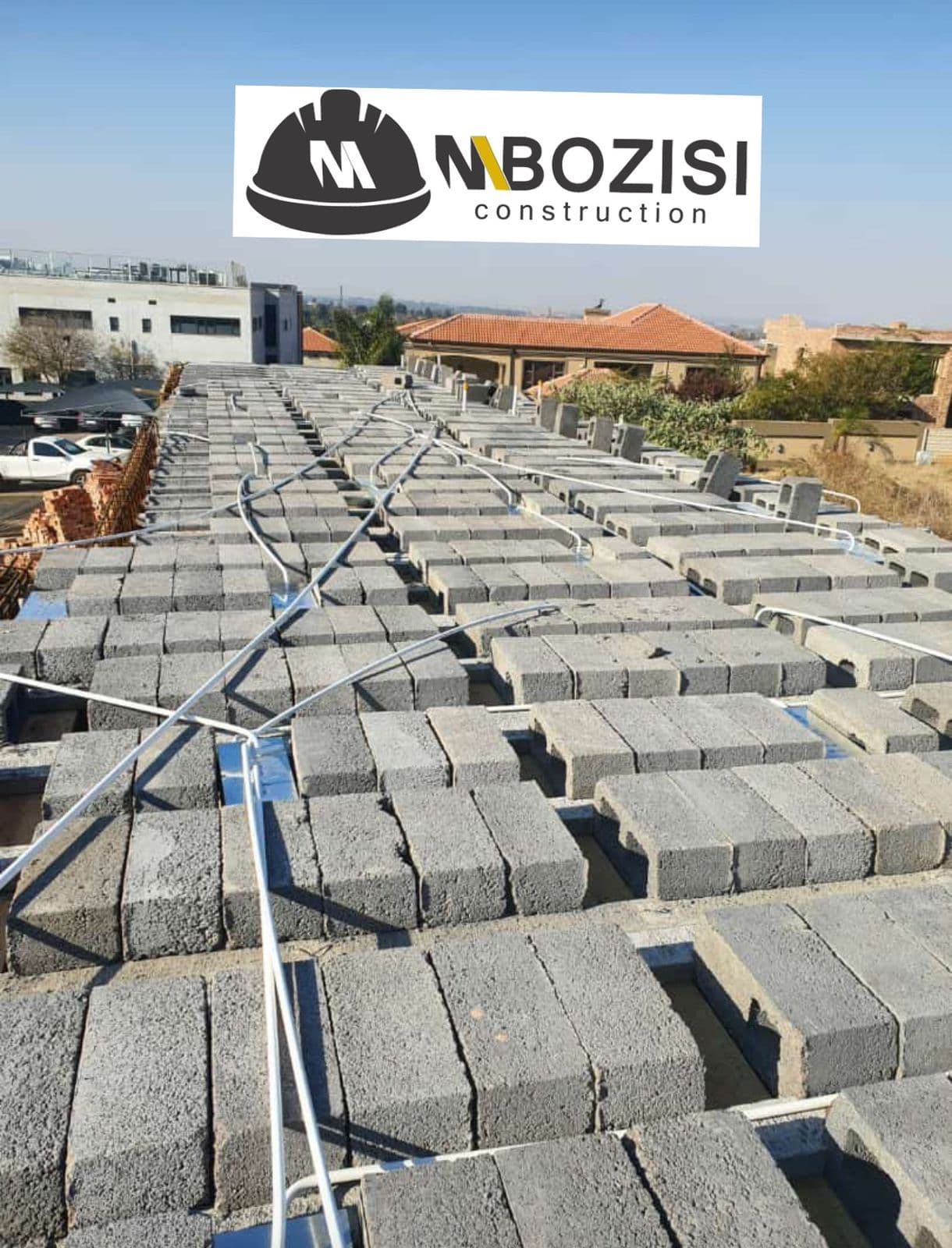 Branded Mbozisi photo of roof slab blocks and conduit laid out before the next construction phase.